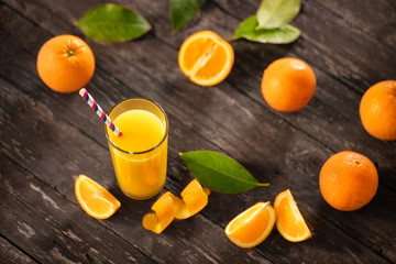 Freshly squeezed orange juice with half oranges on wooden table.