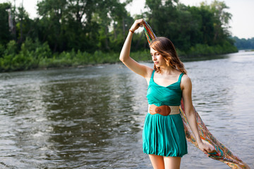 Beautiful Girl Serenely Holding scarf in Breeze by River Lake