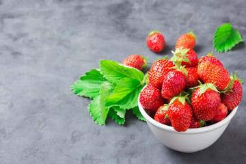 Fresh strawberry in a white bowl on slate background. Selective focus, space for text. Culinary background.