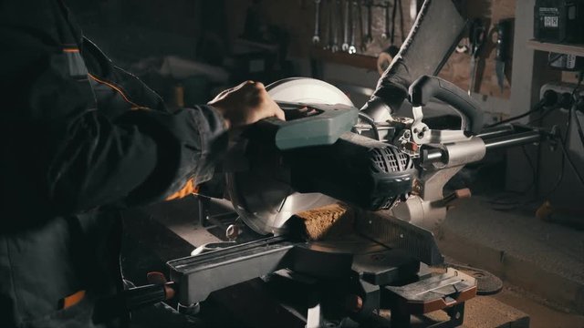 A carpenter uses a cutting saw , to align the edge of the board, furniture manufacturing, lowlight