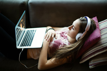 Teenage girl watching a show on her laptop with headphones