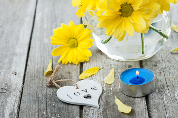 Fresh yellow daisy flowers, sign Love and lit candle