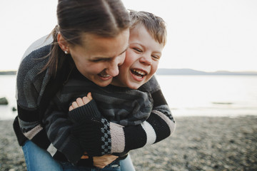 Young mom enjoying cuddling with son outside at the beach