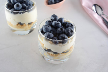 Dessert in a glass with biscuits, cream and blueberries.