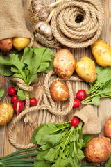 Radish, bag, potato on a wooden background