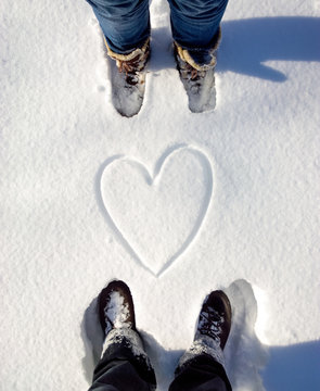 Two people with snow heart between them