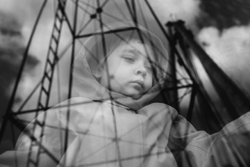 Child gazes sadly through a train window onto which mechanical structures are reflected.