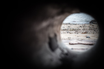 Sicht durch ein altes Rohr am Strand von Rerik mit Blick auf Steine, Muscheln und die Ostsee
