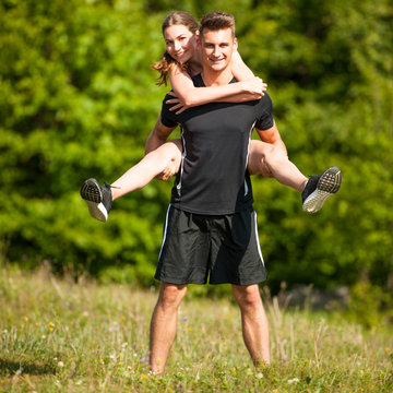 active Playful coupel hiking on a meadow in ratly spring green grass field