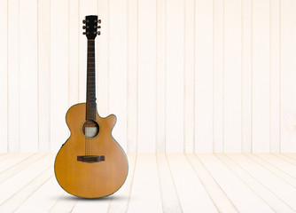 Acoustic guitar on the wooden floor against  wooden wall background.