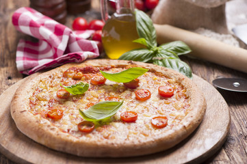 Italian pizza with tomato topped with melted golden cheese, herbs and basil