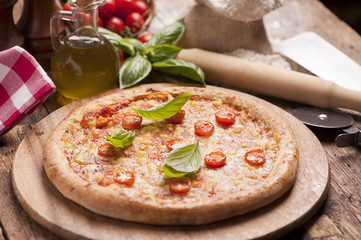 Italian pizza with tomato topped with melted golden cheese, herbs and basil