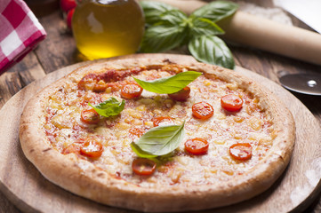 Italian pizza with tomato topped with melted golden cheese, herbs and basil