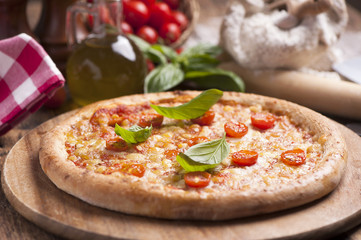 Italian pizza with tomato topped with melted golden cheese, herbs and basil