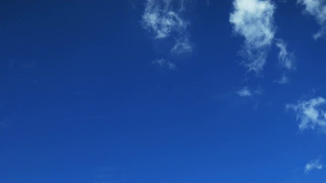 Time lapse clip of white fluffy clouds over blue sky