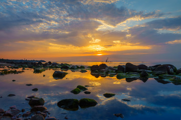 Fototapeta na wymiar Sunset over the sea, stones at foreground