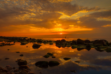 Fototapeta na wymiar Sunset over the sea, stones at foreground