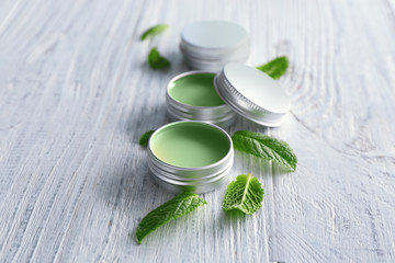 Containers with lemon balm salve and leaves on wooden table - obrazy, fototapety, plakaty