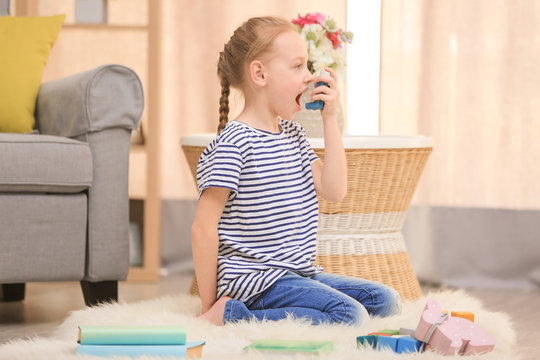 Girl using inhaler during asthmatic attack at home