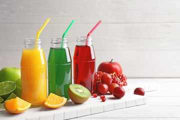 Delicious juices in bottles and fruits on wooden board