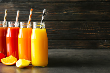 Delicious juices in bottles and fruits on table