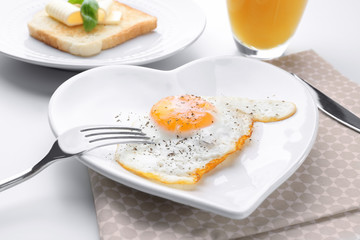 Cutlery and plate with over hard fried egg on light table
