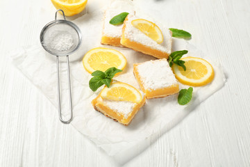 Delicious lemon pie bars and sieve with powdered sugar on wooden table