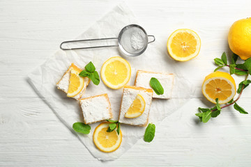 Delicious lemon pie bars and sieve with powdered sugar on wooden table