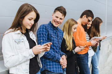 Group of teenagers sitting outdoors using their mobile phones.