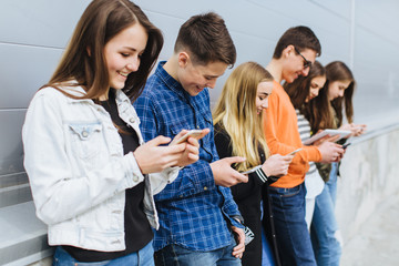 Group of teenagers sitting outdoors using their mobile phones.