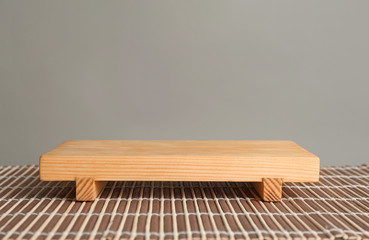 Wooden board on bamboo mat against grey background