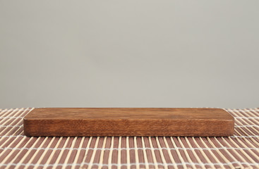 Wooden board on bamboo mat against grey background