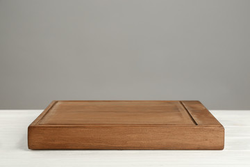 Wooden board on table against grey background