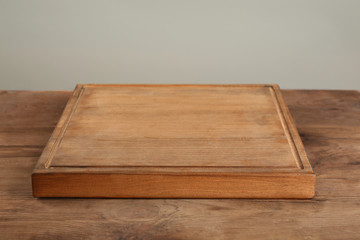 Wooden board on table against grey background