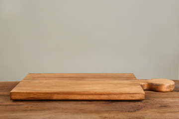 Wooden board on table against grey background