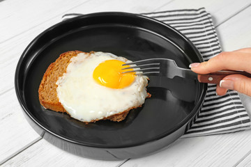 Woman eating over easy egg in kitchen