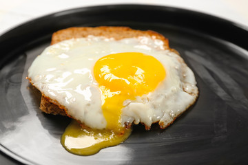Delicious over easy egg with bread slice on plate, closeup