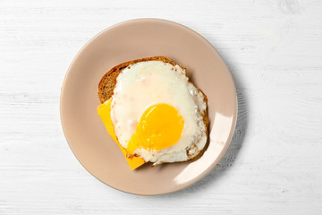 Delicious over easy egg with bread and cheese on wooden background