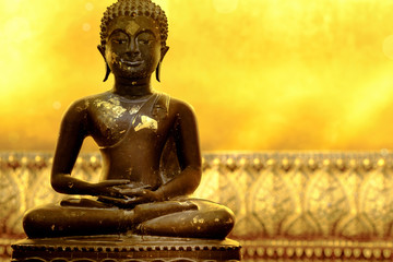 Fototapeta premium Buddha statue of meditation pose in peaceful atmosphere. Golden background is part of huge reclining Buddha statue in a famous temple in Bangkok , Thailand and popular tourist place