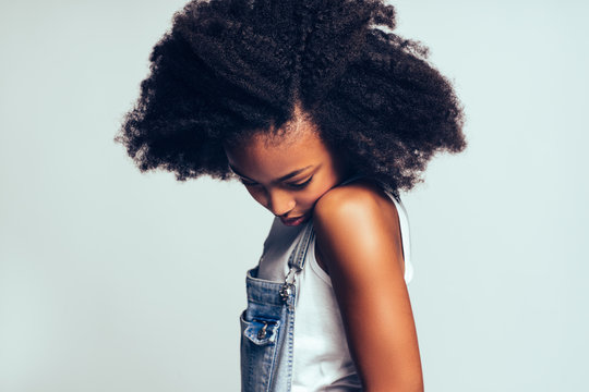 Shy Young African Girl Standing Sideways Against A Gray Backgrou