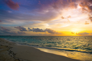 Landscape of beautiful sunset in Maldives island sandy beach with colorful sky over wavy sea