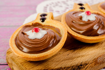 Tartlets in the form of spoons, with sweet chocolate hazelnut paste on a cutting board. Top view. Close-up.
