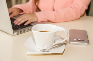 Close up of businesswoman hand working and holding with one hand a cup of coffe. Business concept