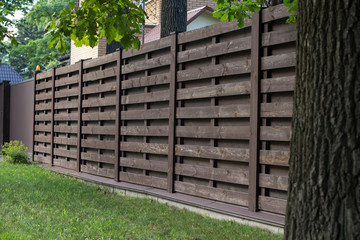 Wooden fence in Scandinavian style, on a green lawn