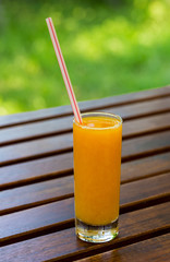 Orange juice on wood table background. Juice on a green background outdoors