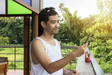 Man holding mobile phone and check social network beside wooden bar.