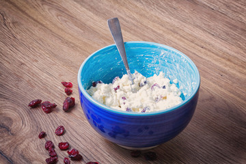dairy dietary healthy breakfast product cottage cheese with red cranberries in blue ceramic bowl.