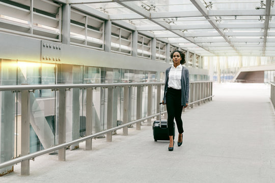 Young woman with luggage walking on terminal, preparing for business trip