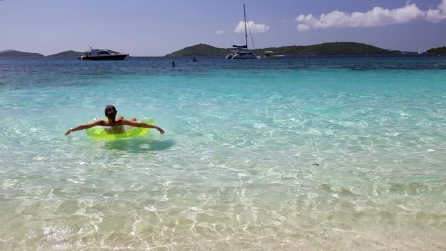 woman relaxing in raft on tropical beach, honeymoon beach, st john