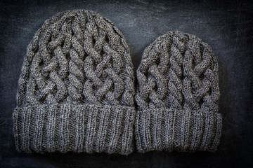 Two sizes of hand knit woolen hats with cables. One for a child, the other for an adult.